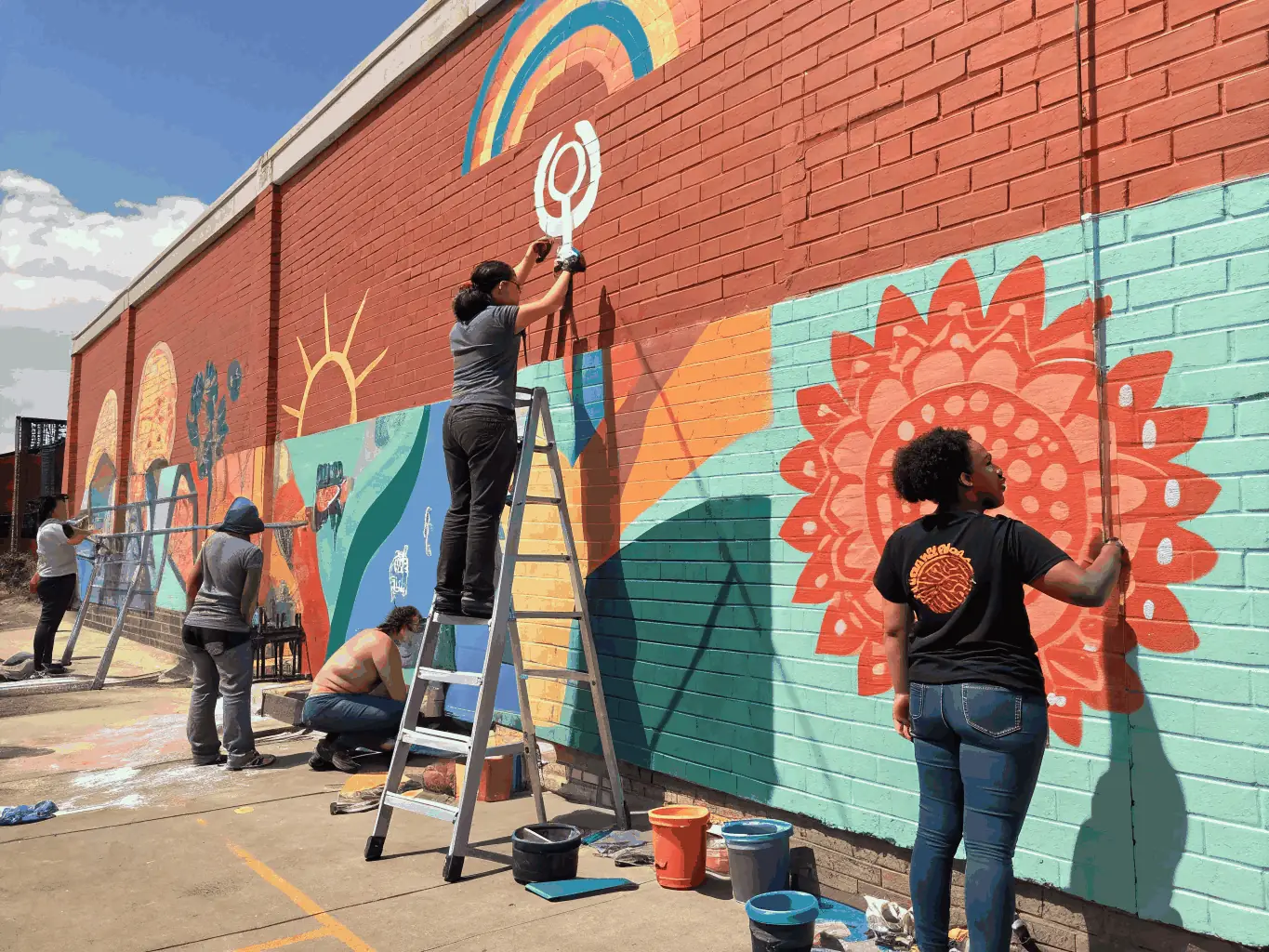 A photograph capturing an artistic action organized by ATELIER DU MOULIN GRAND, showing participants actively involved in creating a public art installation.