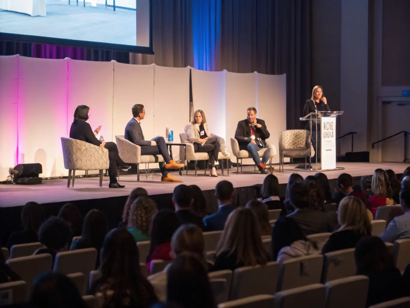 A photograph capturing a vibrant art conference hosted by ATELIER DU MOULIN GRAND, featuring artists and attendees engaged in a panel discussion.
